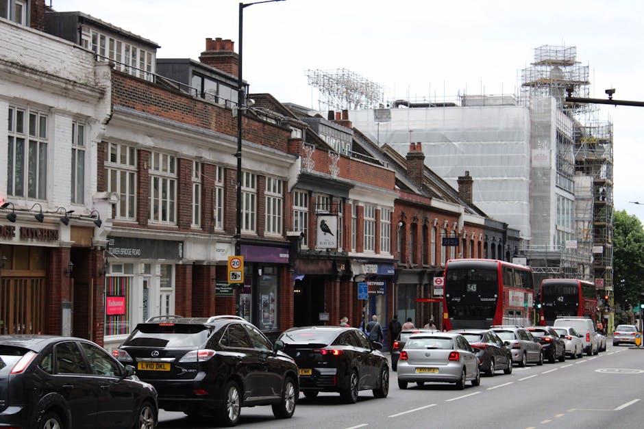 A street scene on Holloway Road featuring a multi-storey brick and stone building with ornately designed windows and a domed rooftop structure. In the foreground, a white van with the branding of Man